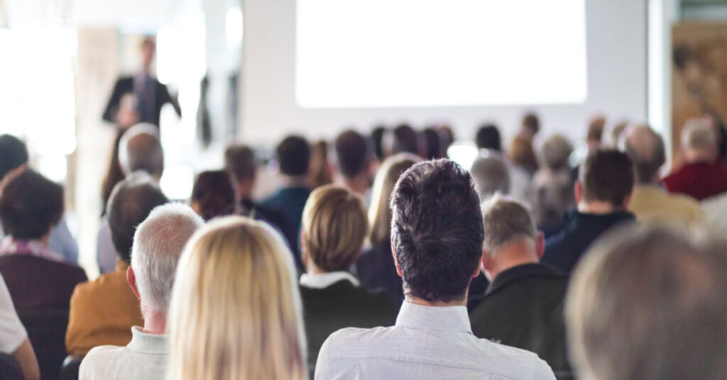 A male speaker is presenting at a business conference with the audience like Community Summit 2023 in the conference room.
