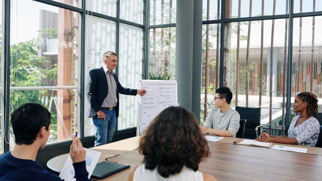 Team leader conducting employee training session in modern conference room, discussing strategy and communication techniques—ideal for ERP change management and user adoption planning.