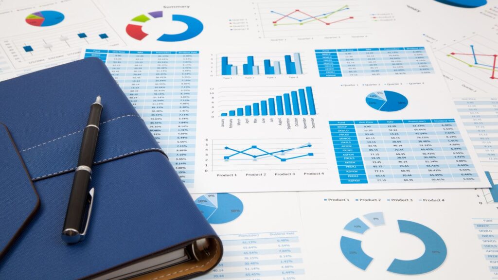 Charts and graphs displaying business performance data next to a notebook and pen, illustrating the benefits of Business Central SaaS such as enhanced reporting, seamless collaboration, and continuous security updates.