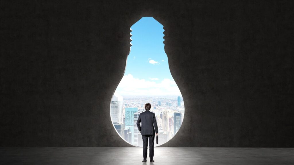 Businessman standing in front of a lightbulb-shaped window overlooking a city skyline, symbolizing vision, innovation, and the future potential of cloud-based ERP solutions like Business Central SaaS.