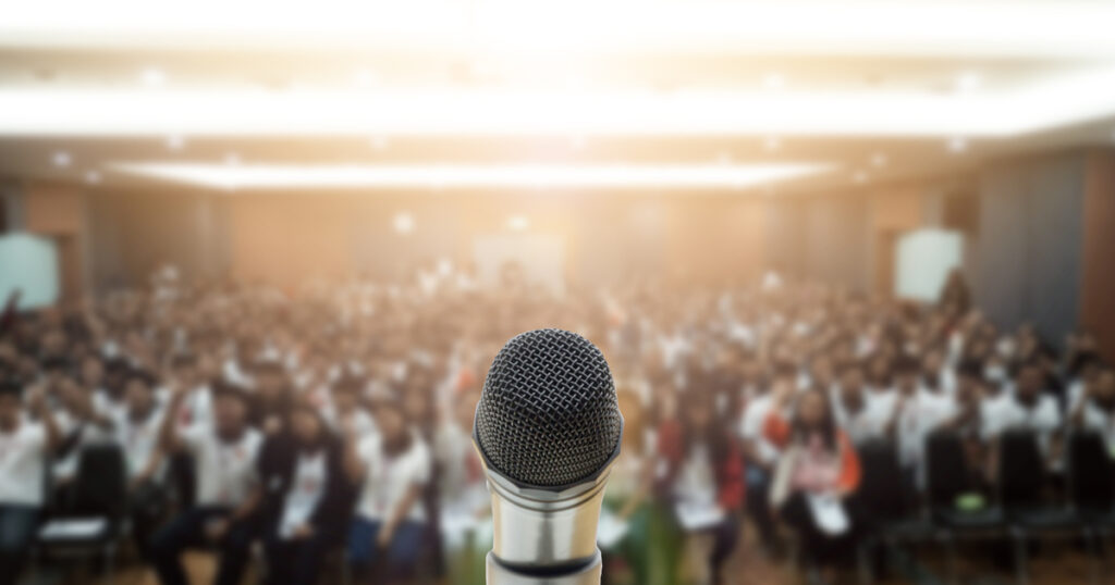 Microphone over an abstract blurred photo of a community summit conference hall
