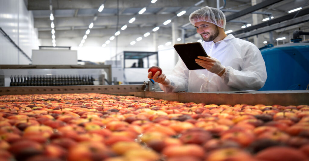 Technologist doing food quality control of apple fruit production in food processing plant.