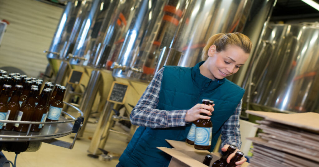 A young female packaging worker packing bottles into a box | Food and Beverage Profit Margins