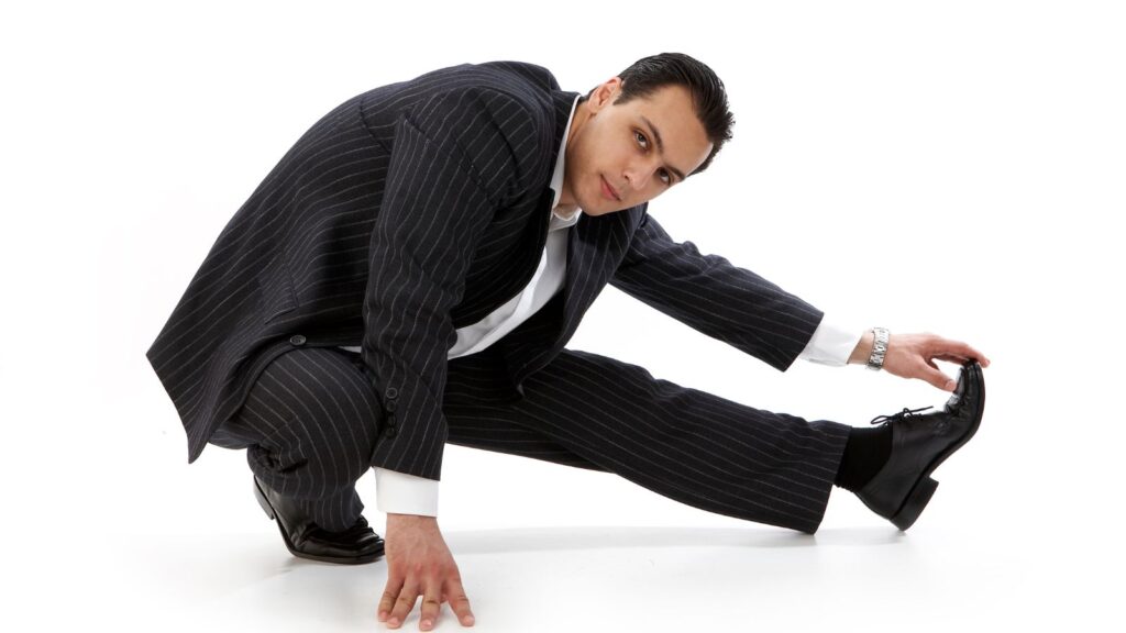 Image of man in a suit stretching showing his flexibility