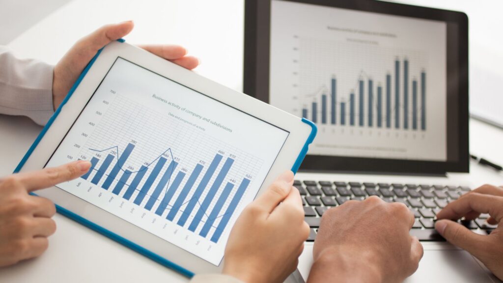 Close-up of professionals analyzing business performance graphs and charts on tablet and laptop screens, highlighting the importance of Dynamics 365 BC Health Checks.