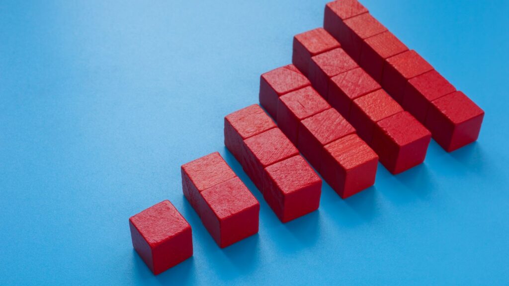 One Size Doesn't Fit All: How Business Central Can Adapt to Any Company's Size 8 Red building blocks arranged in ascending steps on a blue background, symbolizing business growth and scalability—representing the concept that Microsoft Dynamics 365 Business Central can scale with businesses of any size.