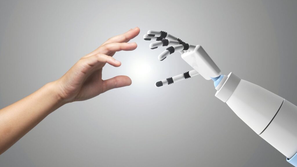 ERP Knowledge Transfer in Manufacturing: How to Prevent Disruption When People Leave 3 A human hand reaching out to connect with a robotic hand, symbolizing human-AI collaboration, innovation, and the future of technology integration.