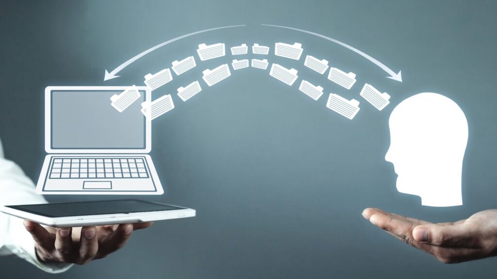 ERP Knowledge Transfer in Manufacturing: How to Prevent Disruption When People Leave 1 ERP knowledge transfer in manufacturing illustrated by a digital concept showing data folders moving from a laptop to a human head, symbolizing the sharing of business process expertise and system knowledge.