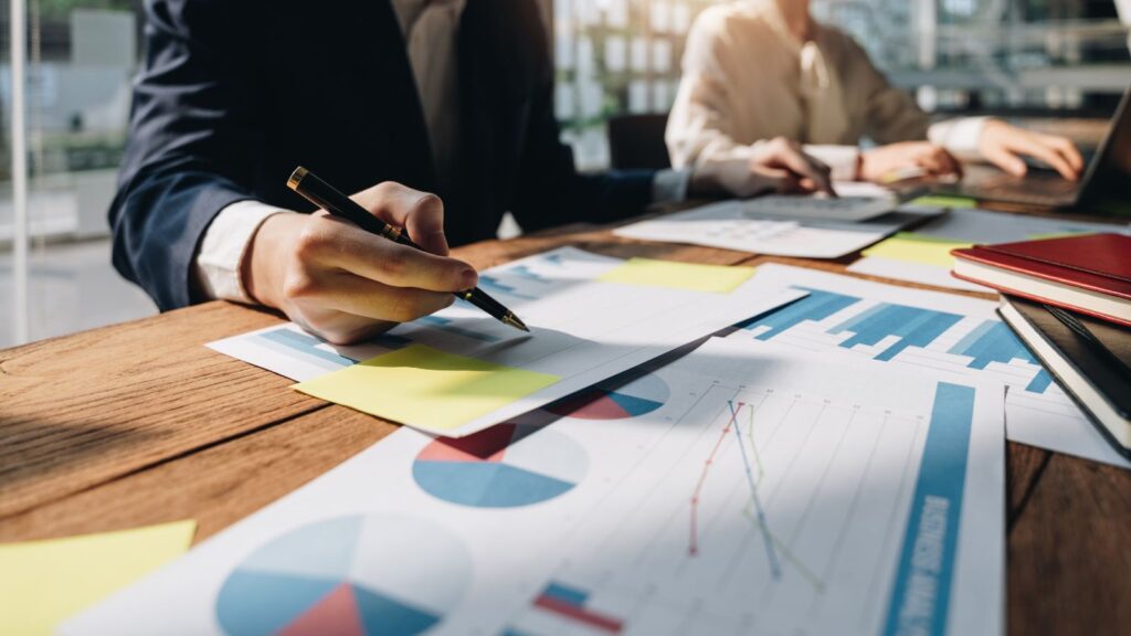 From Shop Floor to Customer Door: ERP-CRM Integration in Manufacturing Excellence 3 Business team reviewing charts, graphs, and financial reports during a consulting meeting to plan strategy and improve performance.