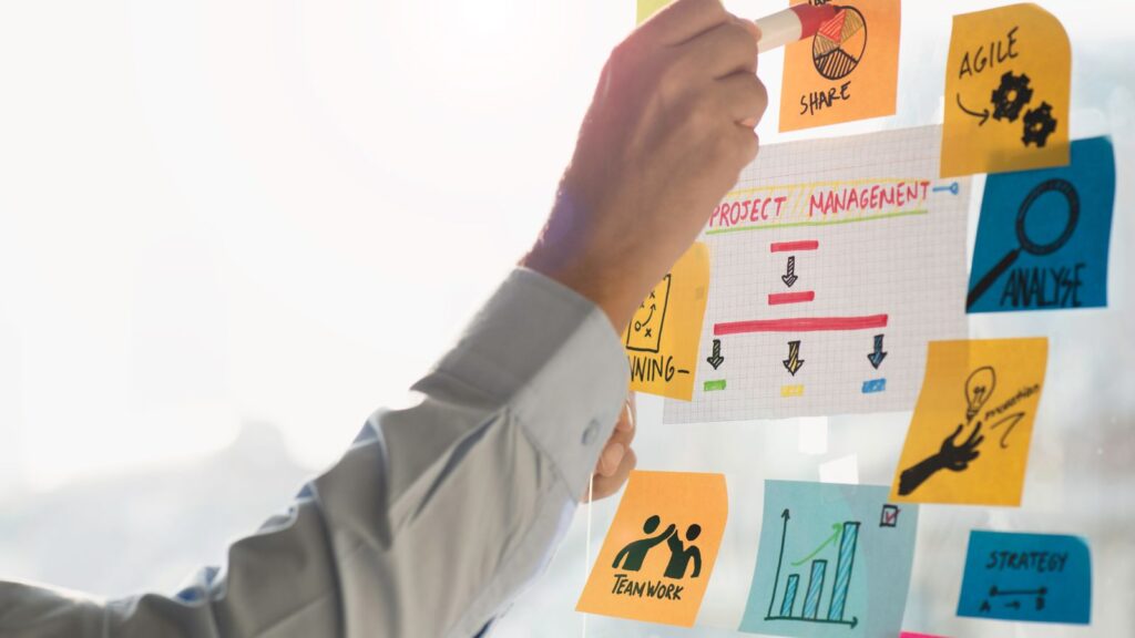 Step-by-Step ERP Migration Roadmap | Move from Legacy ERP to Microsoft Dynamics 365 Business Central 3 Hand arranging sticky notes and charts for project management planning, symbolizing steps in an ERP Migration Roadmap to Microsoft Dynamics 365 Business Central.
