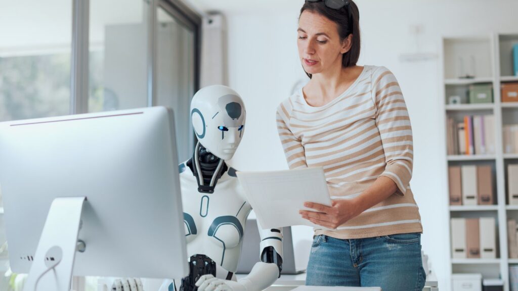 Overcoming Data Migration Challenges: Turning Obstacles into Opportunities 4 Woman collaborating with an AI robot at a computer, representing how artificial intelligence helps solve Data Migration Challenges through automation and efficiency.