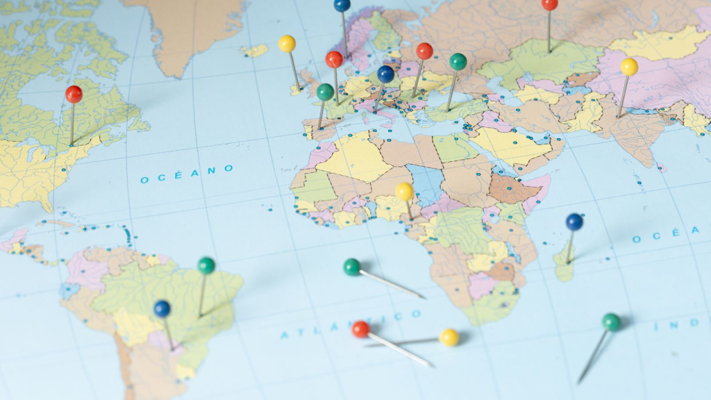 Close-up of a world map with colorful push pins marking multiple global locations across North America, South America, Europe, Africa, and Asia, symbolizing international business expansion, global market presence, travel planning, or worldwide logistics strategy.