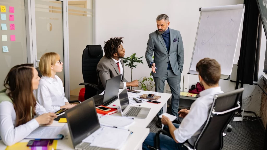 Business leaders collaborating in a strategy meeting, reviewing charts and discussing workforce planning in manufacturing to align teams, skills, and production goals.